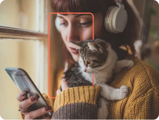 Pet owner holding her cat while using her phone